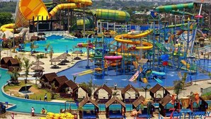 A water park with multiple slides and pools, surrounded by beach huts and umbrellas. - Uptown Hotel (Yangon)