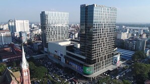 A modern high-rise building with a glass facade, surrounded by other buildings and a church spire in the foreground. - Uptown Hotel (Yangon)