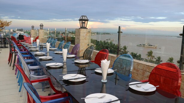 A dining table set with chairs and a view of a body of water. - Uptown Hotel (Yangon)