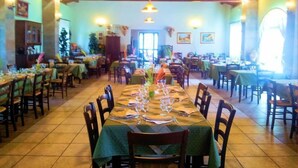 A restaurant with multiple dining tables set for guests, wooden chairs, and a tiled floor. - Le Terre di San Domenico (Augusta)
