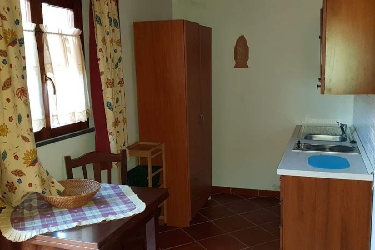 A compact kitchen with a sink, wooden cabinets, and a small table with a basket.