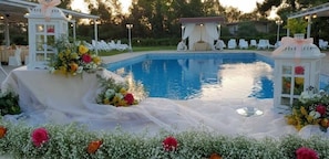 A pool area with a white gazebo, white chairs, and floral decorations. - Le Terre di San Domenico (Augusta)