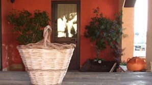 A wicker basket on a table outside a building with a red wall and a door. - Le Terre di San Domenico (Augusta)