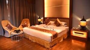 Una habitación de hotel con una cama grande, una silla, una mesita de noche y una lámpara.