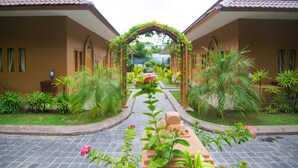 Un patio con un arco central rodeado de abundante vegetación y plantas en macetas.