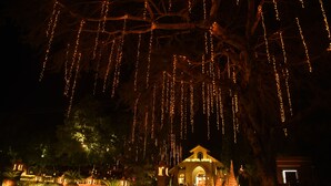 Un hotel con un gran árbol decorado con luces colgantes, una entrada bien iluminada y un estilo arquitectónico tradicional.