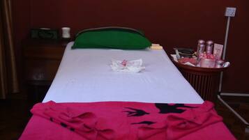 Restful retreat with a single bed, featuring a white mattress and a green pillow, and a small table with a basket of essentials.