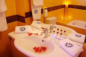 A hotel bathroom with a sink, toilet, and bathtub. There are towels and toiletries on the counter. - Louros (Zakynthos)