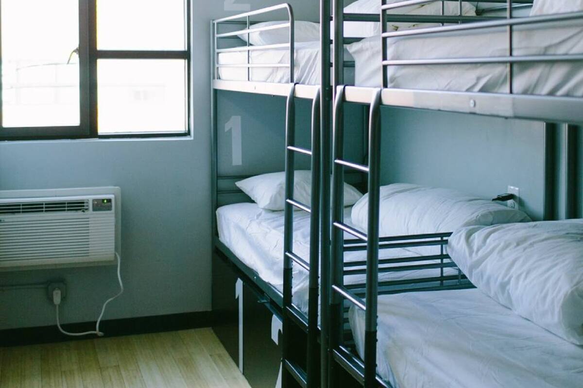 A dormitory room with bunk beds, a window, and a hanging light fixture.