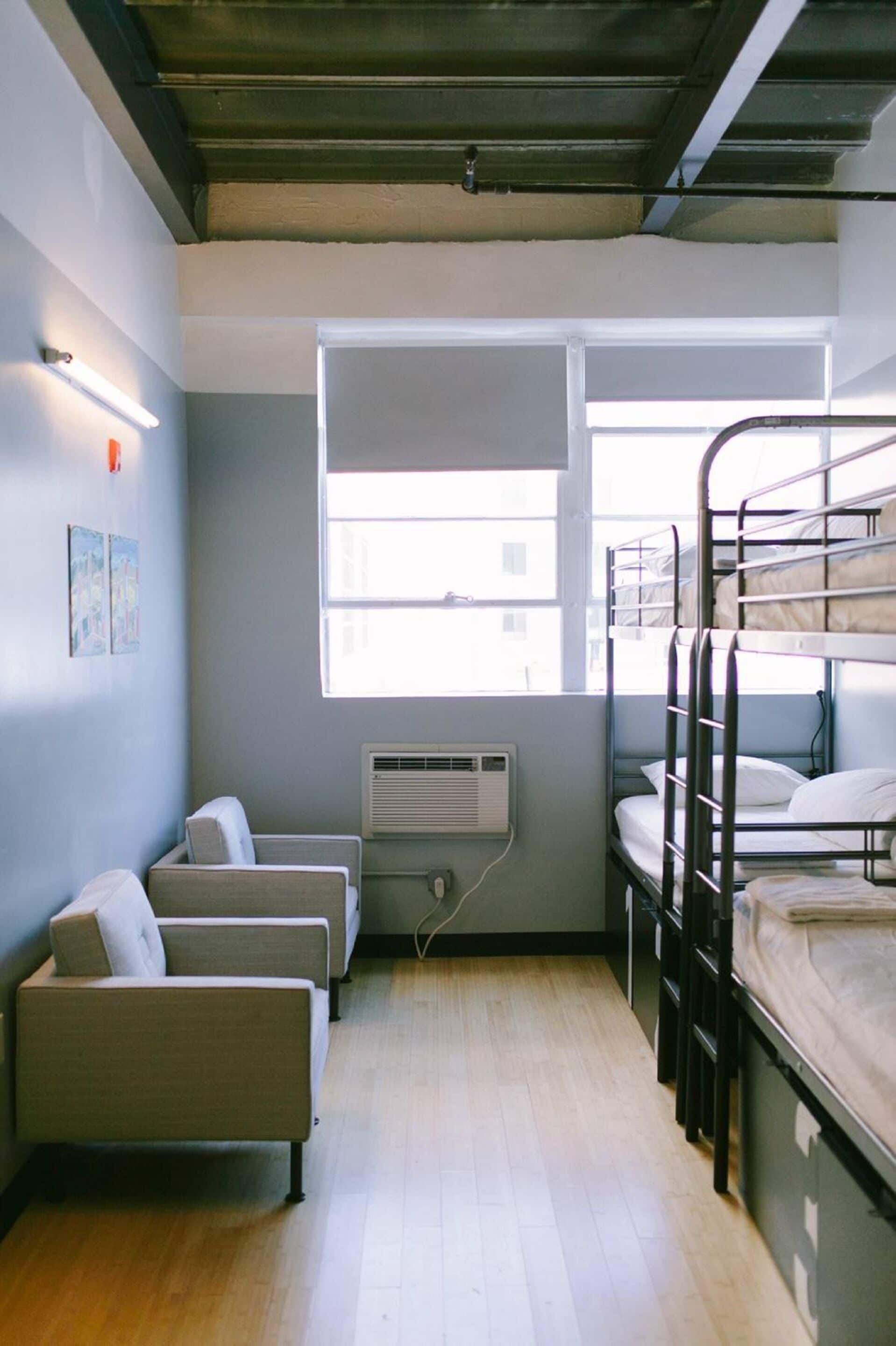 Une chambre de dortoir avec des lits superposés, un bureau, une chaise et une fenêtre.