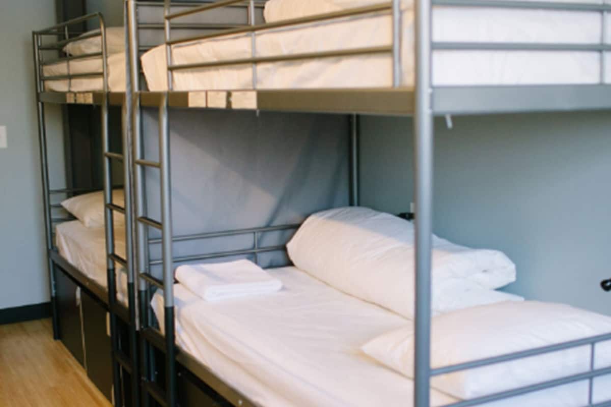 A row of bunk beds in a room with wooden flooring and a gray wall.
