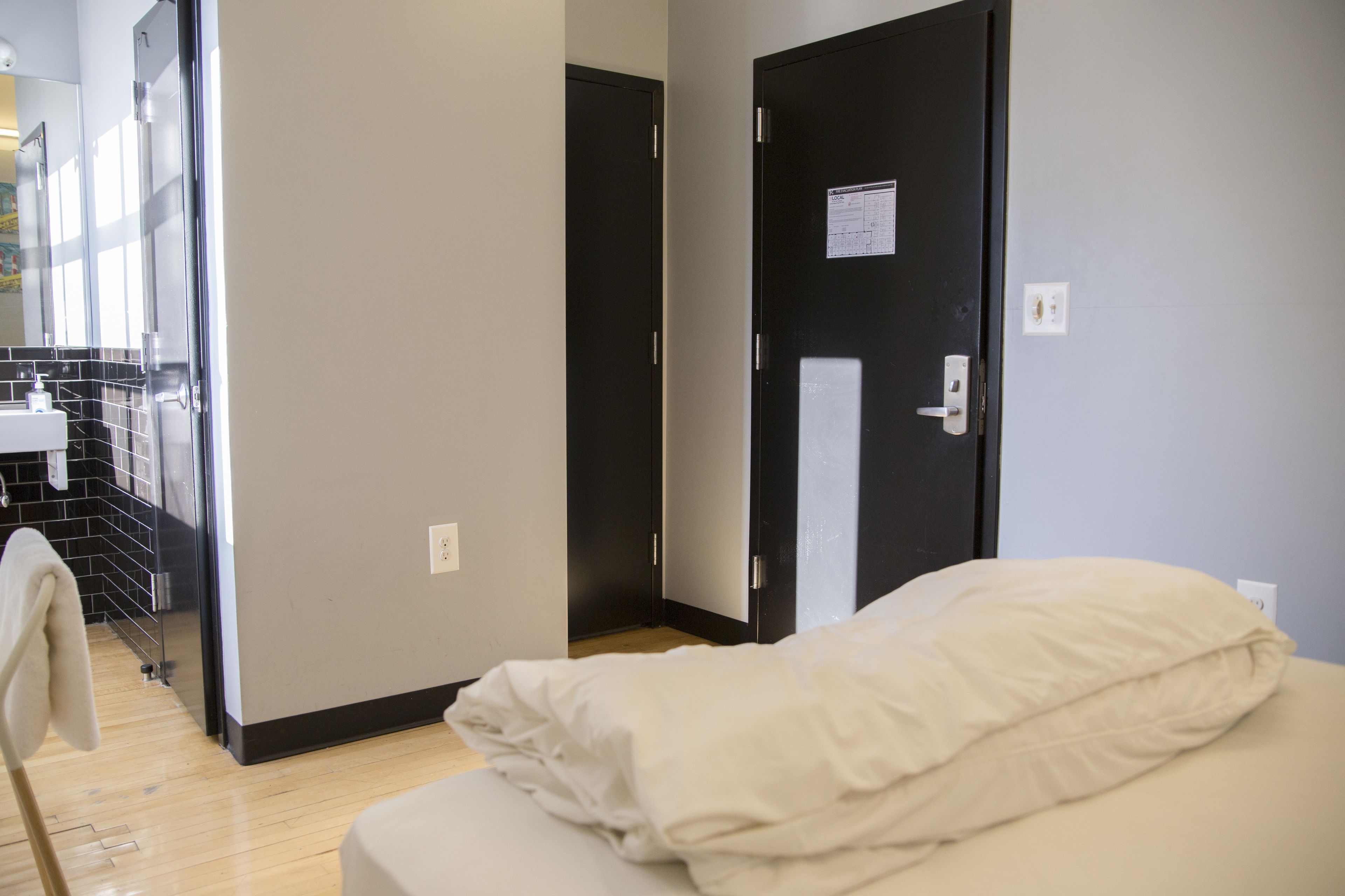 Una habitación de hotel con cama, una puerta y un baño visible a través de una puerta abierta.