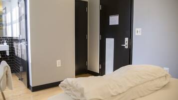 Una habitación de hotel con cama, una puerta y un baño visible a través de una puerta abierta.