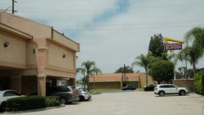 A parking lot with several cars, a building with a sign for 'IN-N-OUT BURGER,' and palm trees in the background. - Mountain Inn (Ontario)