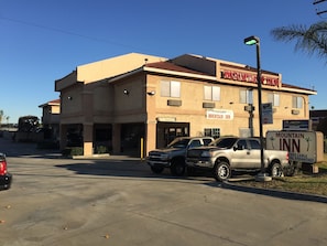 A building with a sign for Mountain Inn, featuring a parking area with several vehicles, a street lamp, and a clear blue sky.