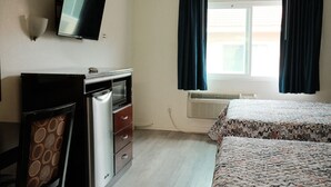 A room with a bed, a desk with a computer, a television, and a window with curtains. - Mountain Inn (Ontario)