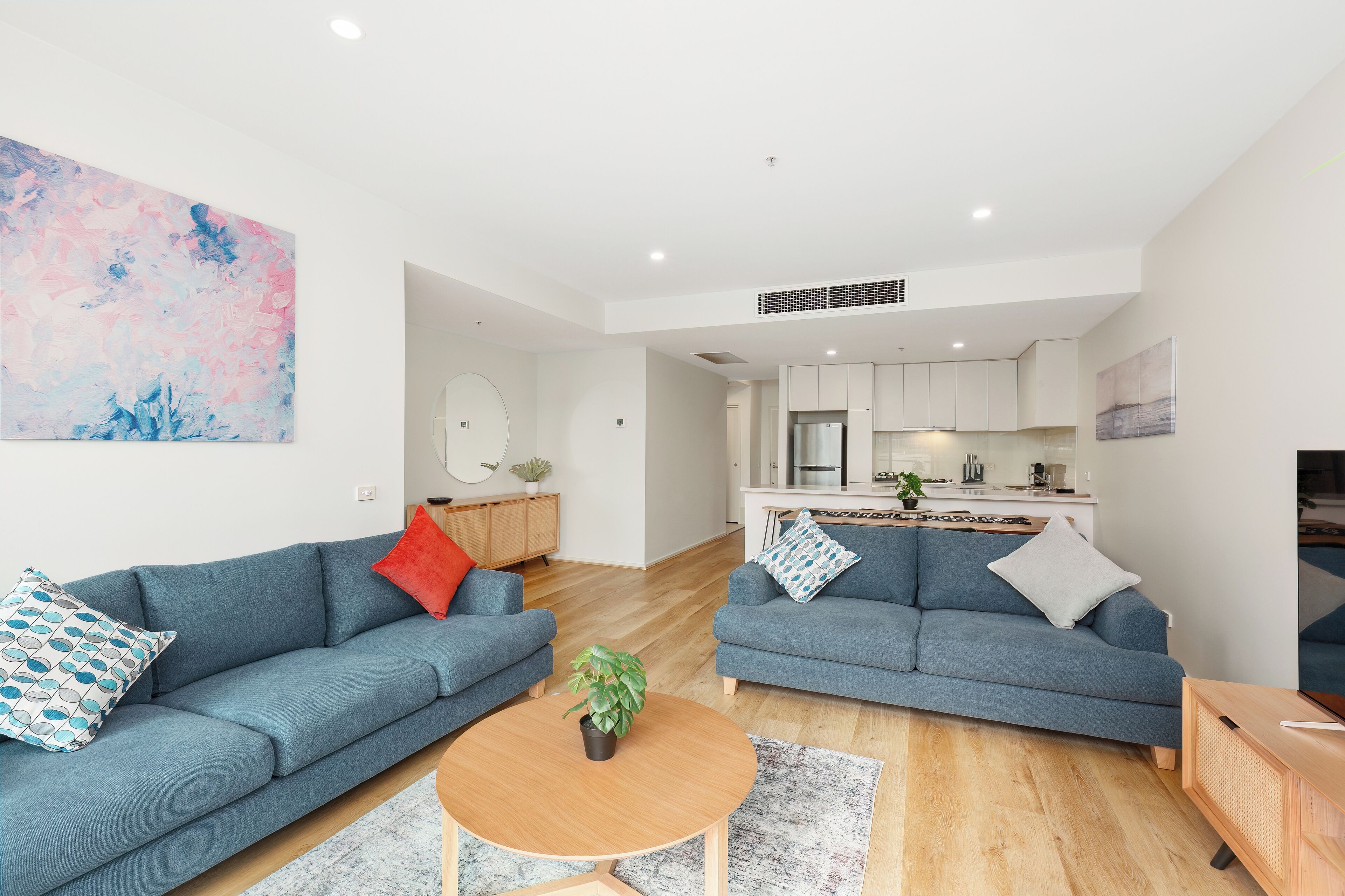 A modern living room with two sofas, a coffee table, and a kitchen in the background.