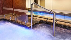 A hot tub with a glass wall and metal railings, surrounded by a tiled floor. - Waterfront Melbourne Apartments (Docklands)