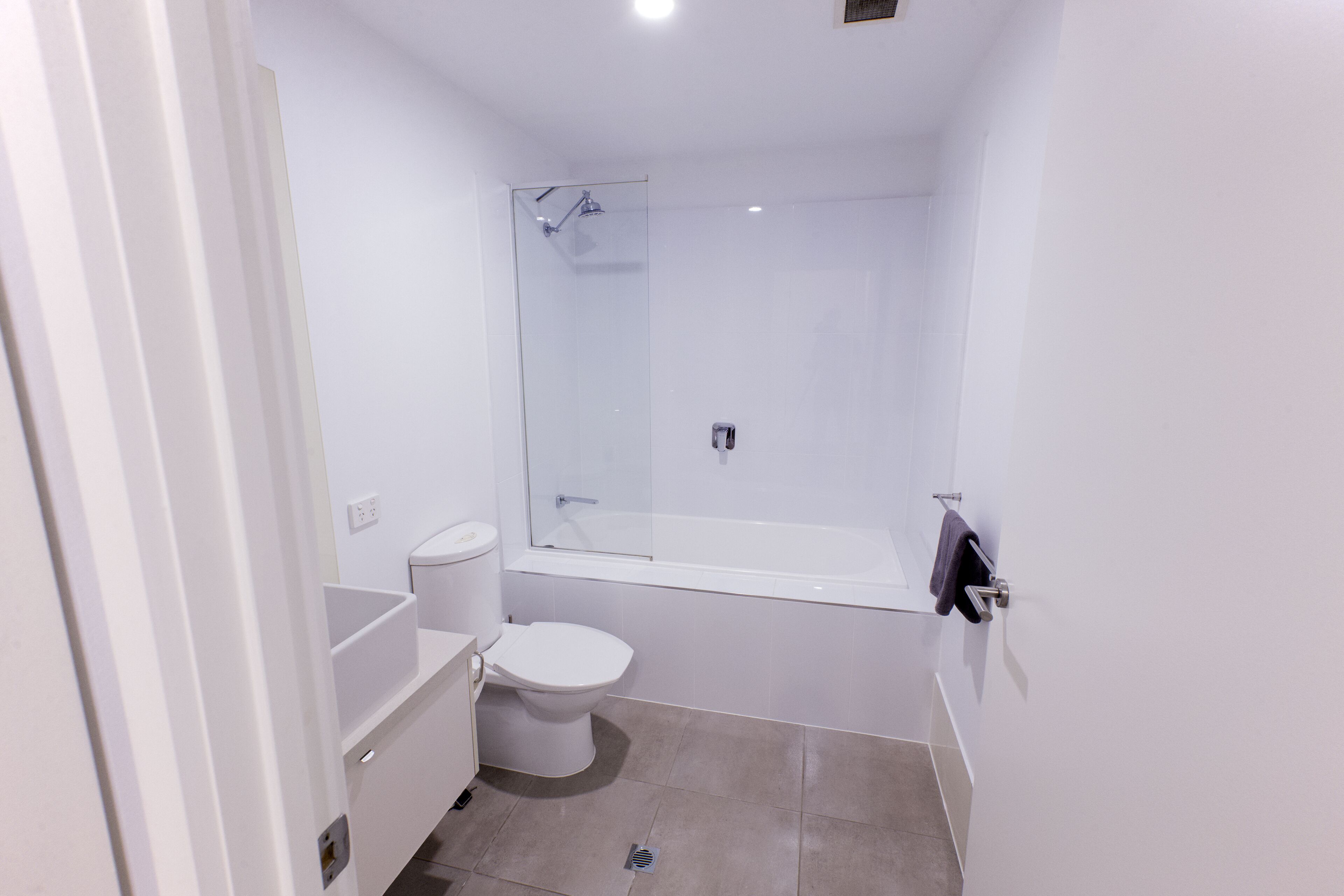 A small, modern bathroom with a toilet, sink, and shower.