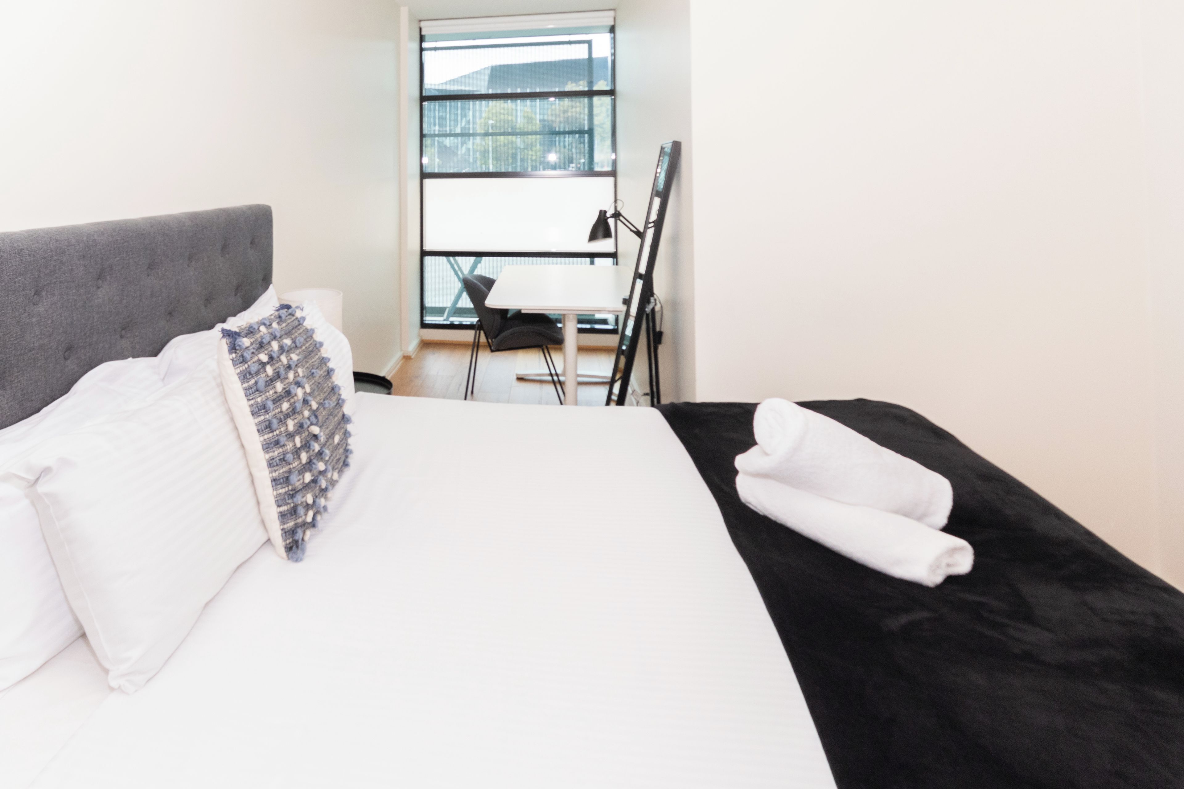 Hotellihuone, jossa on sänky, työpöytä ja tuoli.