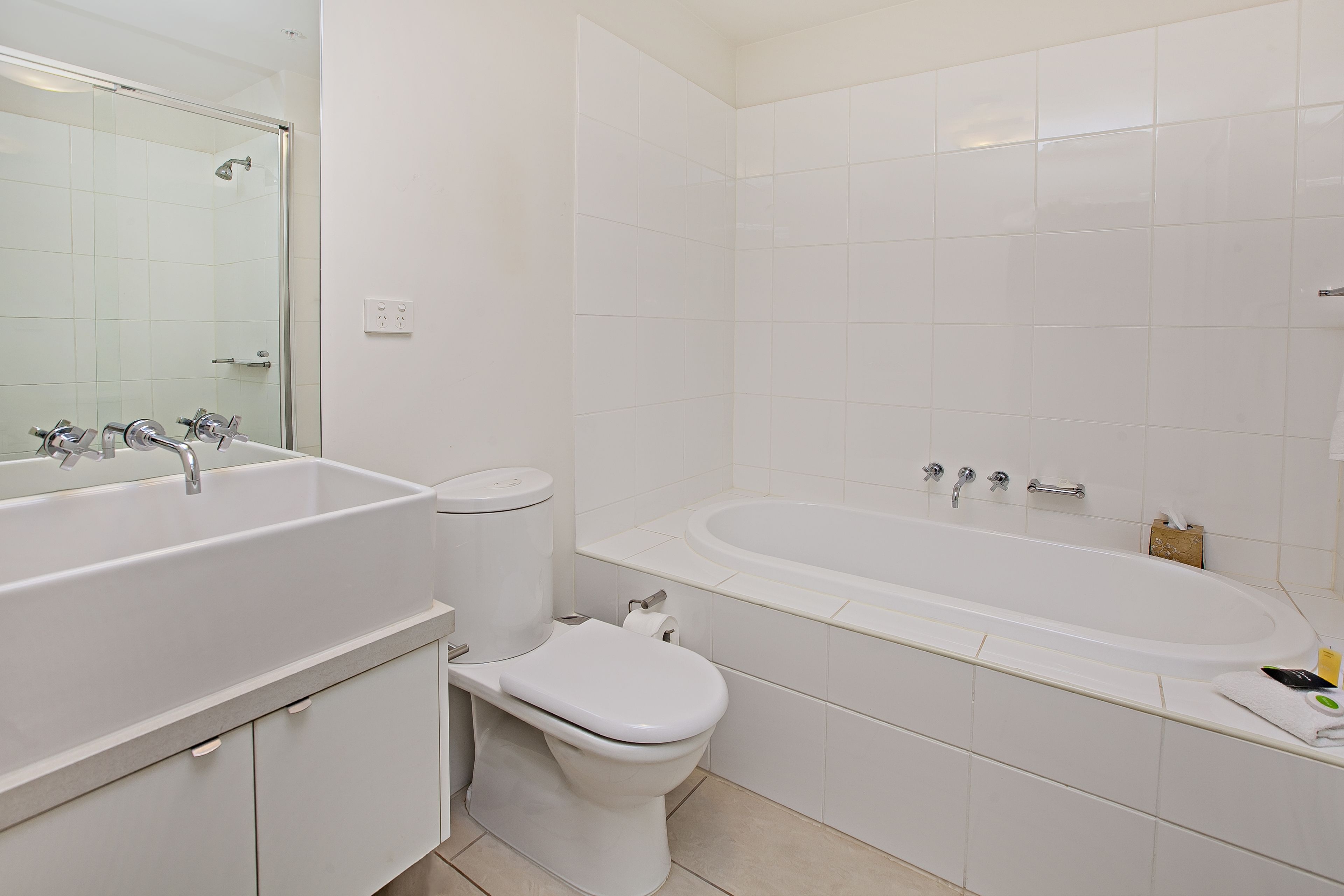 A modern bathroom with a large white bathtub, a separate toilet, and a vanity with a sink.