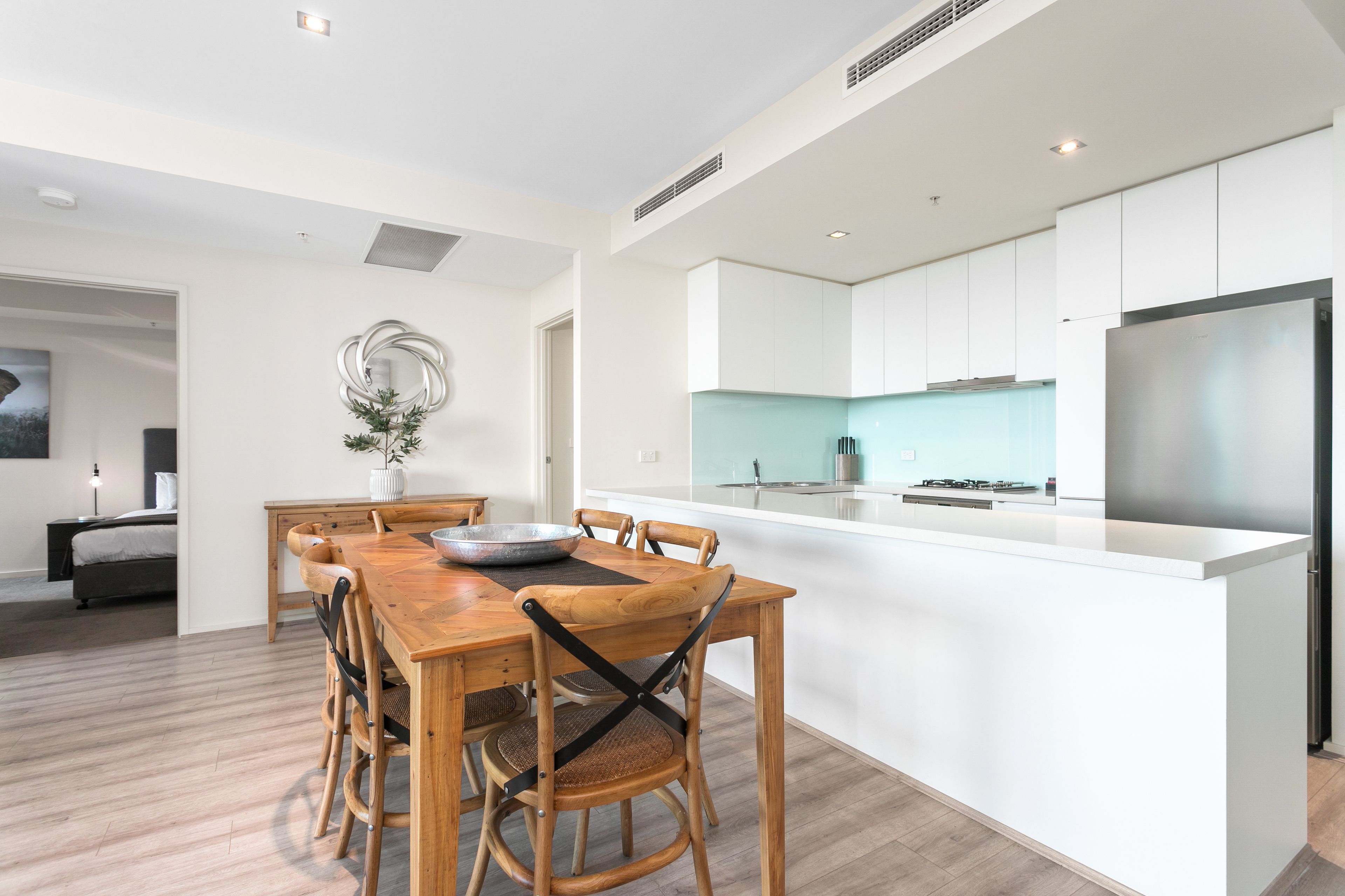 Una cocina moderna con armarios blancos, un refrigerador de acero inoxidable y un salpicadero azul claro.