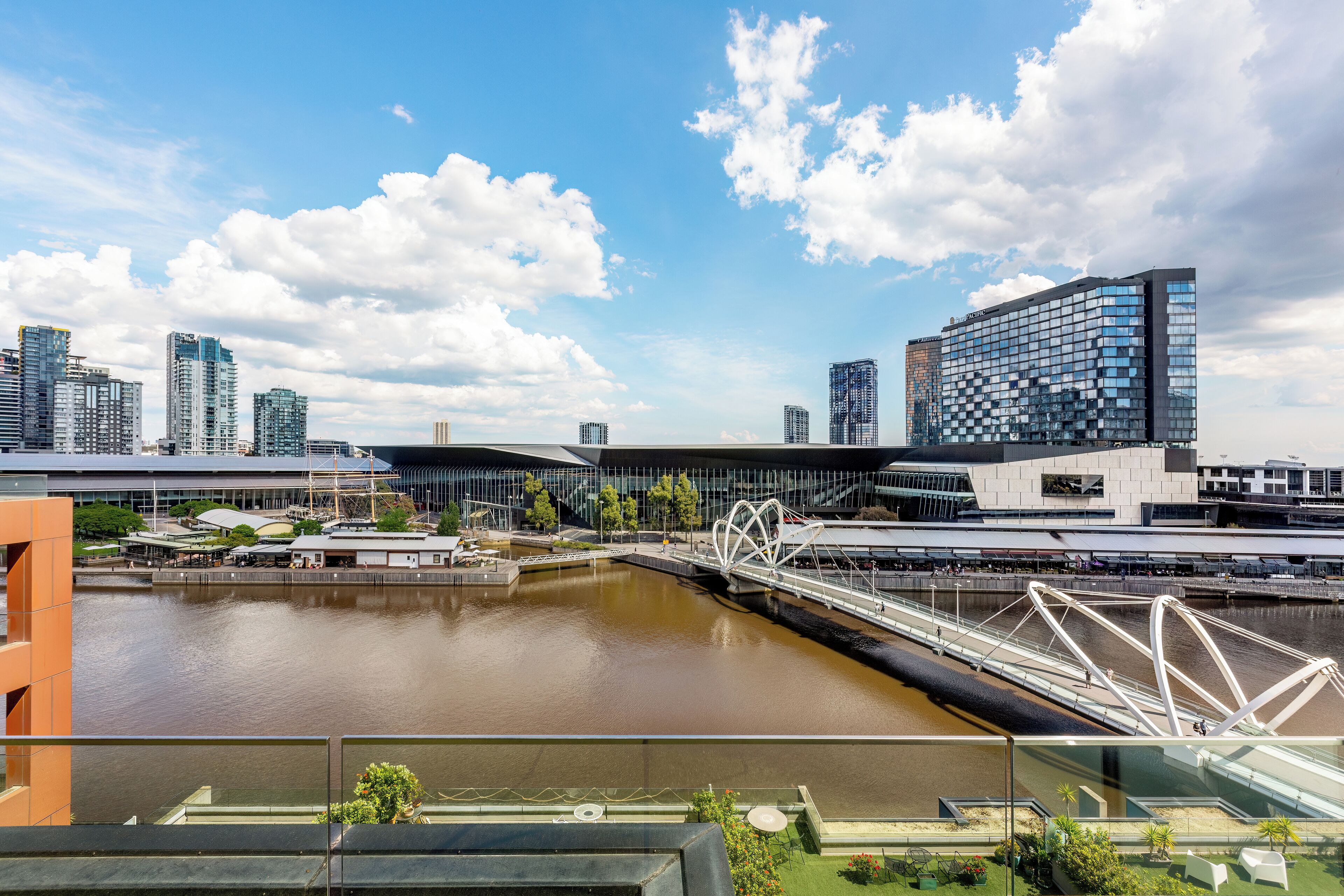 A modern cityscape with a river, a bridge, and high-rise buildings.