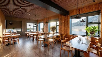 A restaurant with wooden interiors, large windows, and a view of the outdoors.
