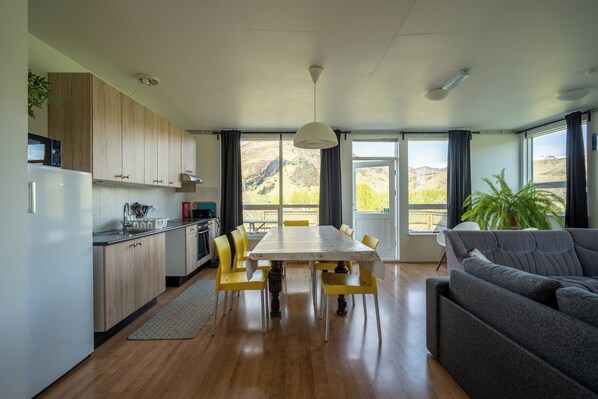 Una cocina moderna con armarios de madera, una mesa de comedor con sillas amarillas y un sofá gris.