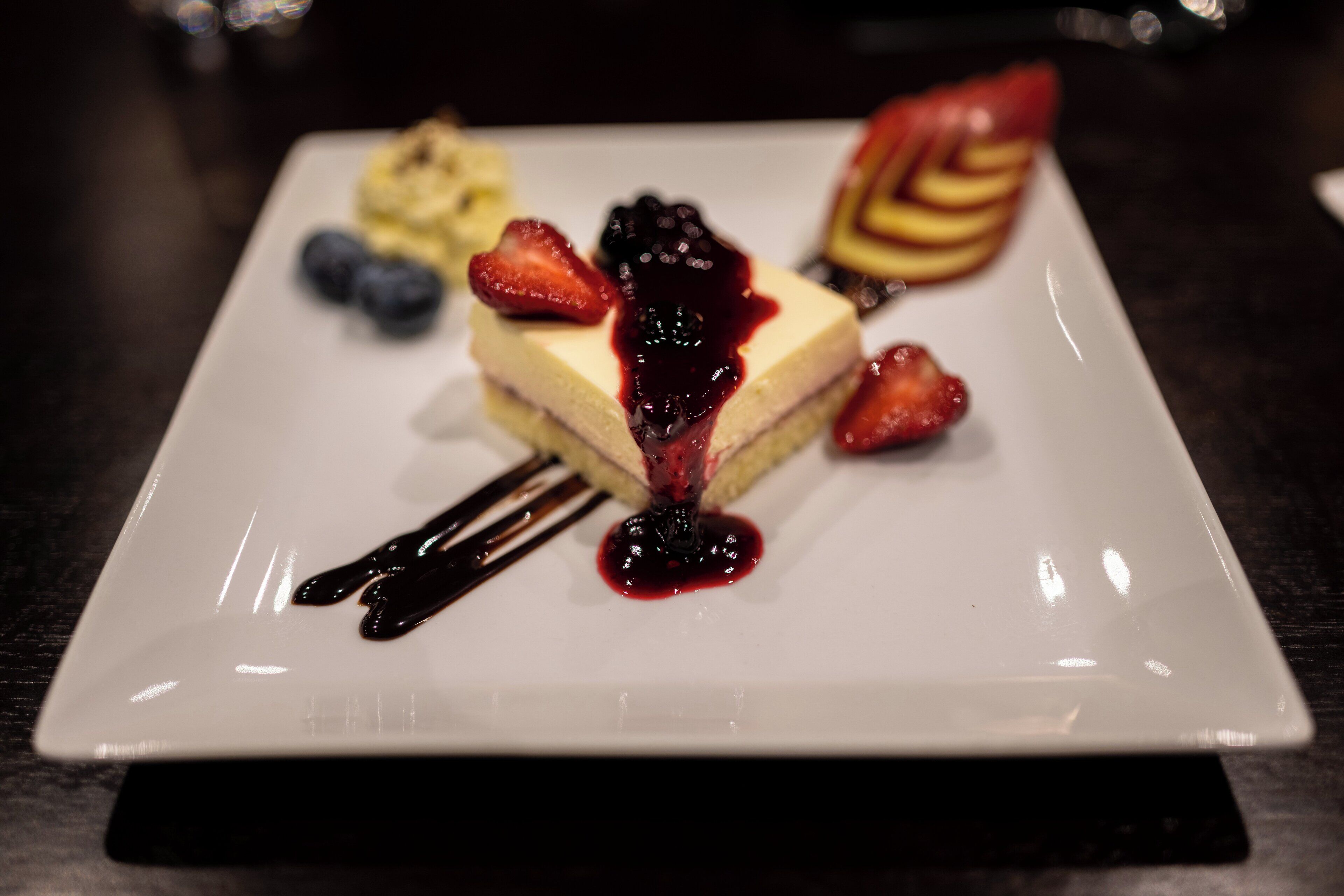 A dessert plate with a cheesecake topped with berries and sauce.