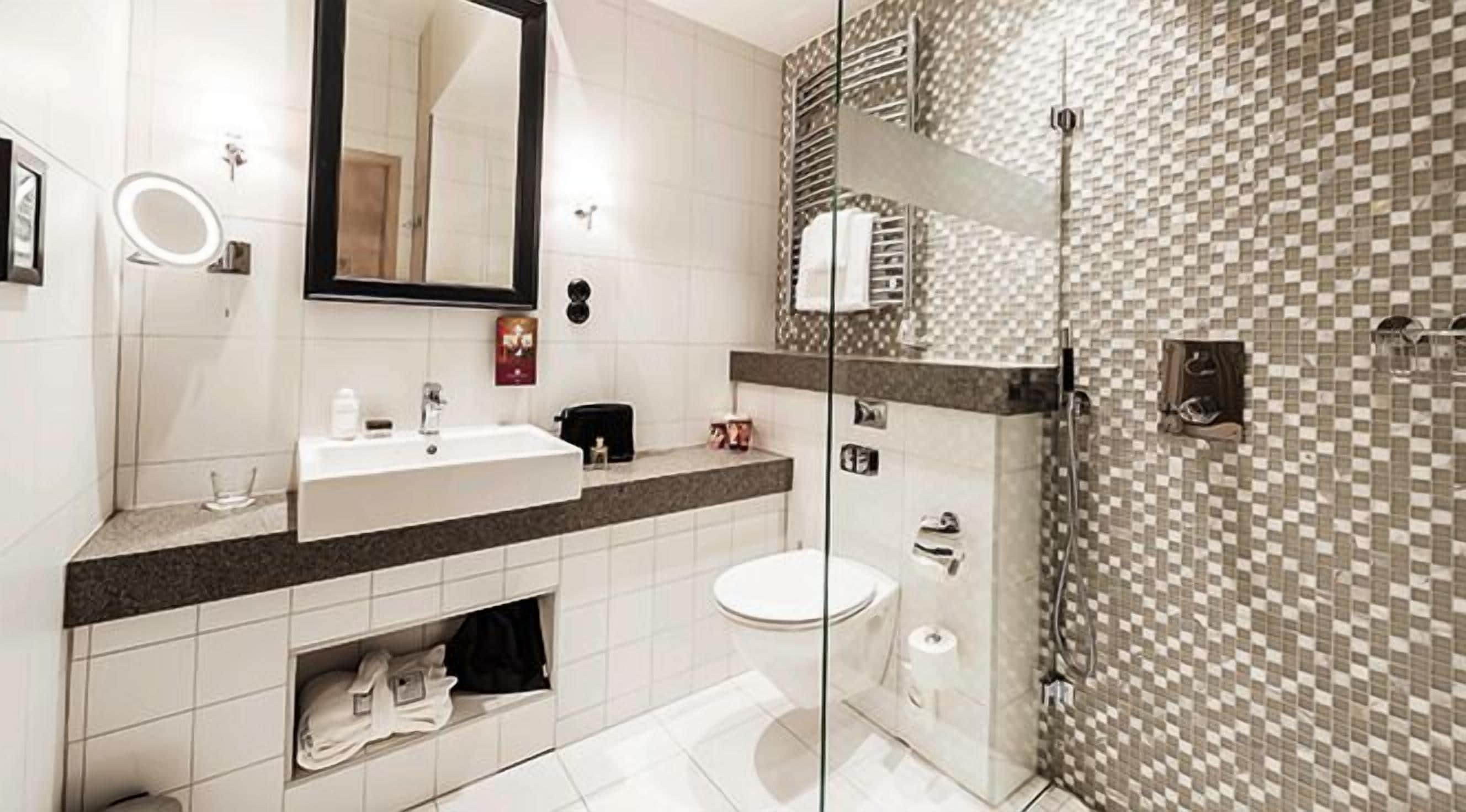 A modern bathroom with a large mirror, a sink, a toilet, and a shower area.