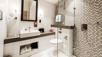 Un baño moderno con un espejo grande, un lavabo, un inodoro y una zona de ducha.