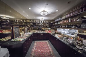 A buffet area with a variety of food items and beverages, a central chandelier, and a patterned rug on the floor. - Hotel Kungsträdgården – The King´s Garden (Stockholm)