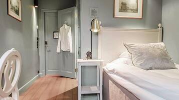 A bedroom with a bed, a nightstand, a lamp, a chair, and a door leading to another room.