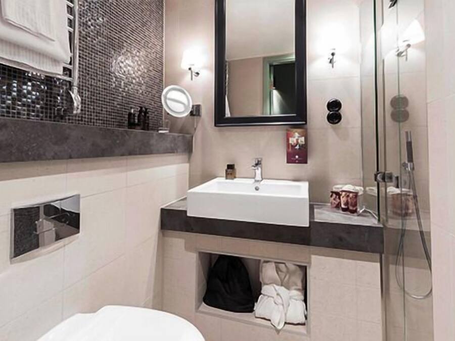 A modern bathroom with a white sink, a mirror, and a glass shower enclosure.