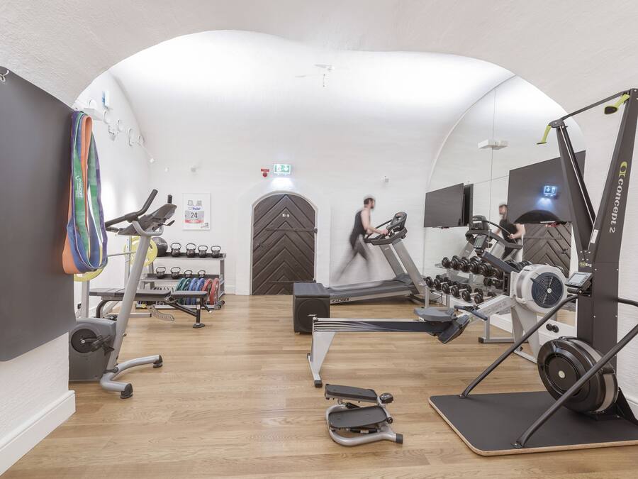 Un gimnasio con máquinas de cardio, equipo de levantamiento de pesas y un espejo grande.