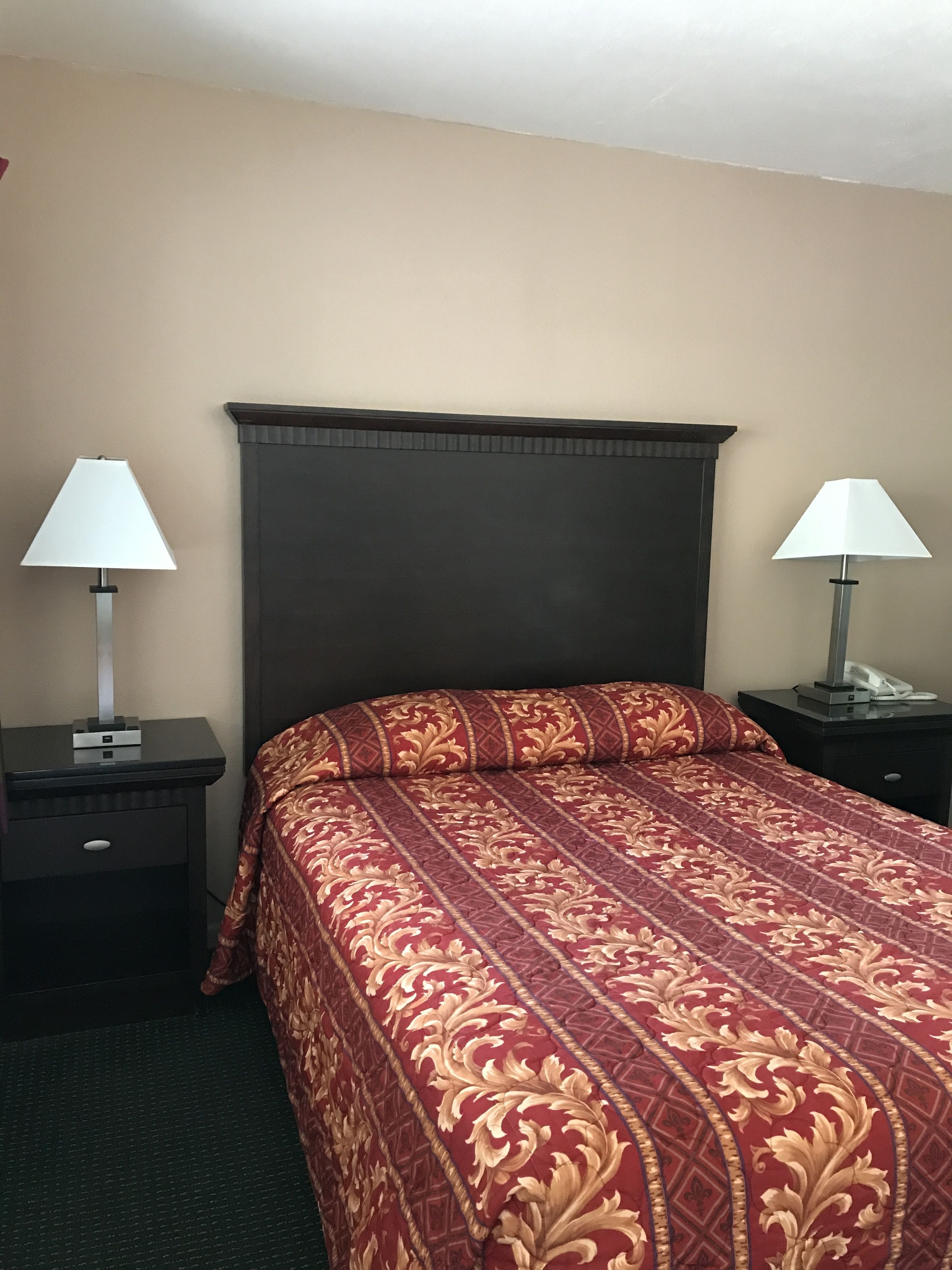 A hotel room with a large bed, two bedside tables, and lamps.