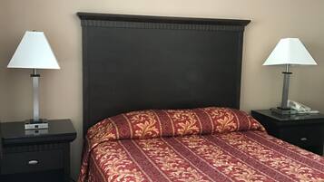 A hotel room with a large bed, two bedside tables, and lamps.