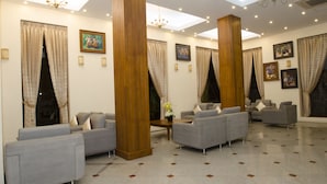 A spacious lobby with multiple seating areas, large wooden columns, and ceiling lights. - Reno Hotel (Yangon)