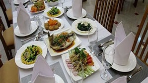 A dining table set with plates of food, glasses, and cutlery. - Reno Hotel (Yangon)