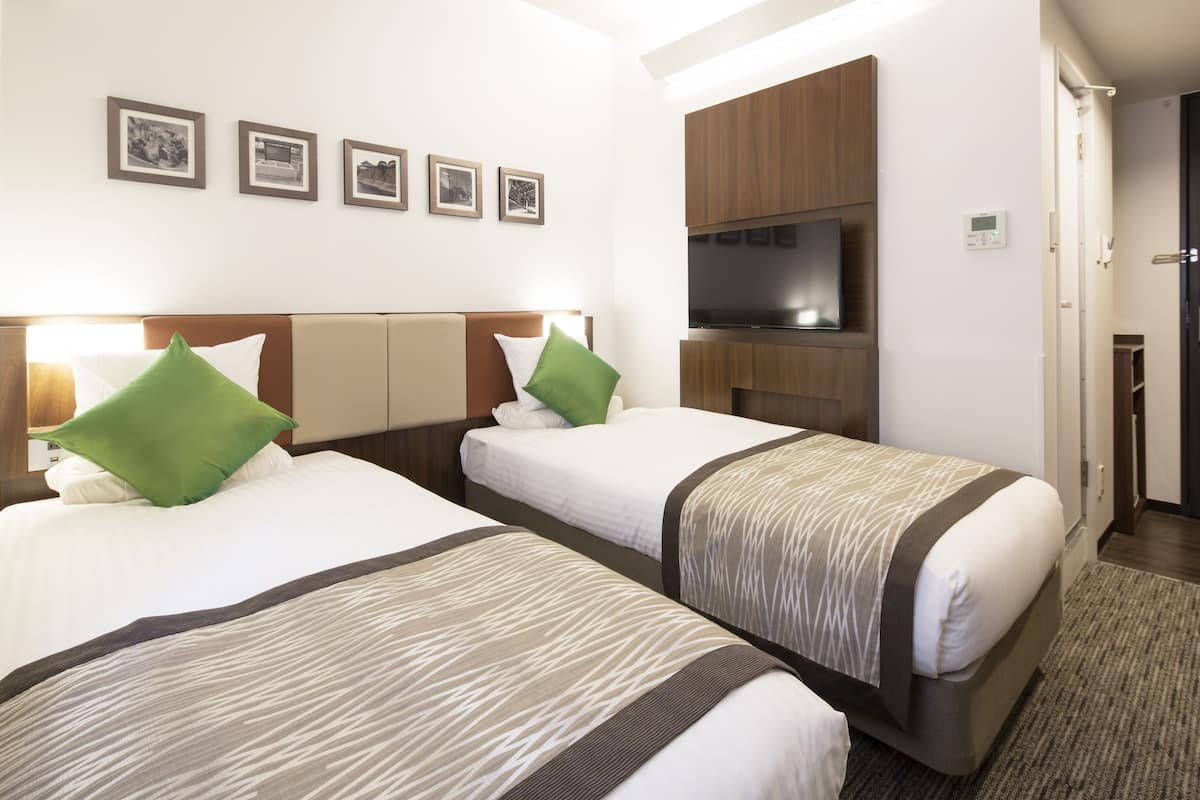A hotel room with two beds, a TV, and a wardrobe.