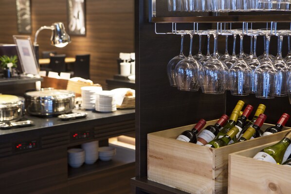 Uma área de bar com garrafas de vinho e copos.