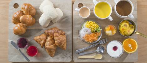 Two wooden serving boards with food items, including croissants, bread rolls, and various breakfast dishes.
