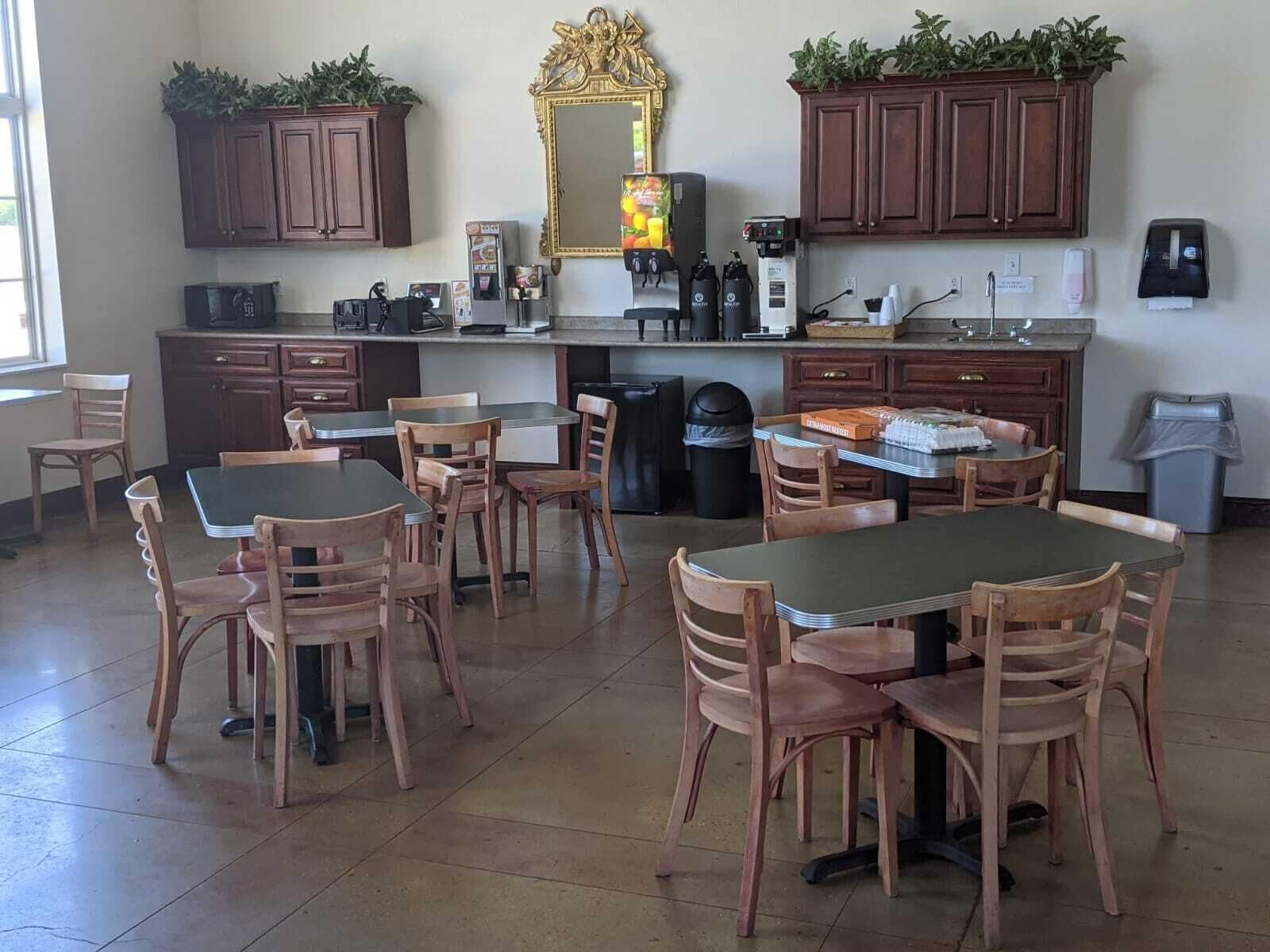 A spacious kitchen with wooden cabinets, a large mirror, and a dining area with wooden tables and chairs.