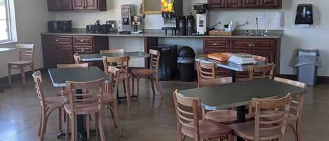 A spacious kitchen with wooden cabinets, a large mirror, and a dining area with wooden tables and chairs.