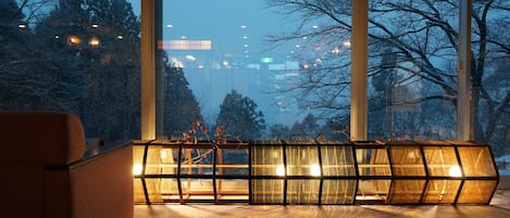 A modern interior with large windows, a sofa, and a unique illuminated structure.