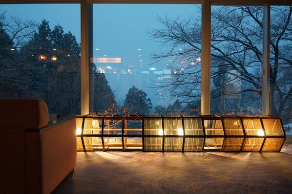 Un intérieur moderne avec de grandes fenêtres, un canapé et une structure originale illuminée.