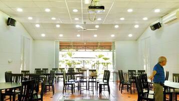 A dining area with tables and chairs, ceiling fans, and a projector.
