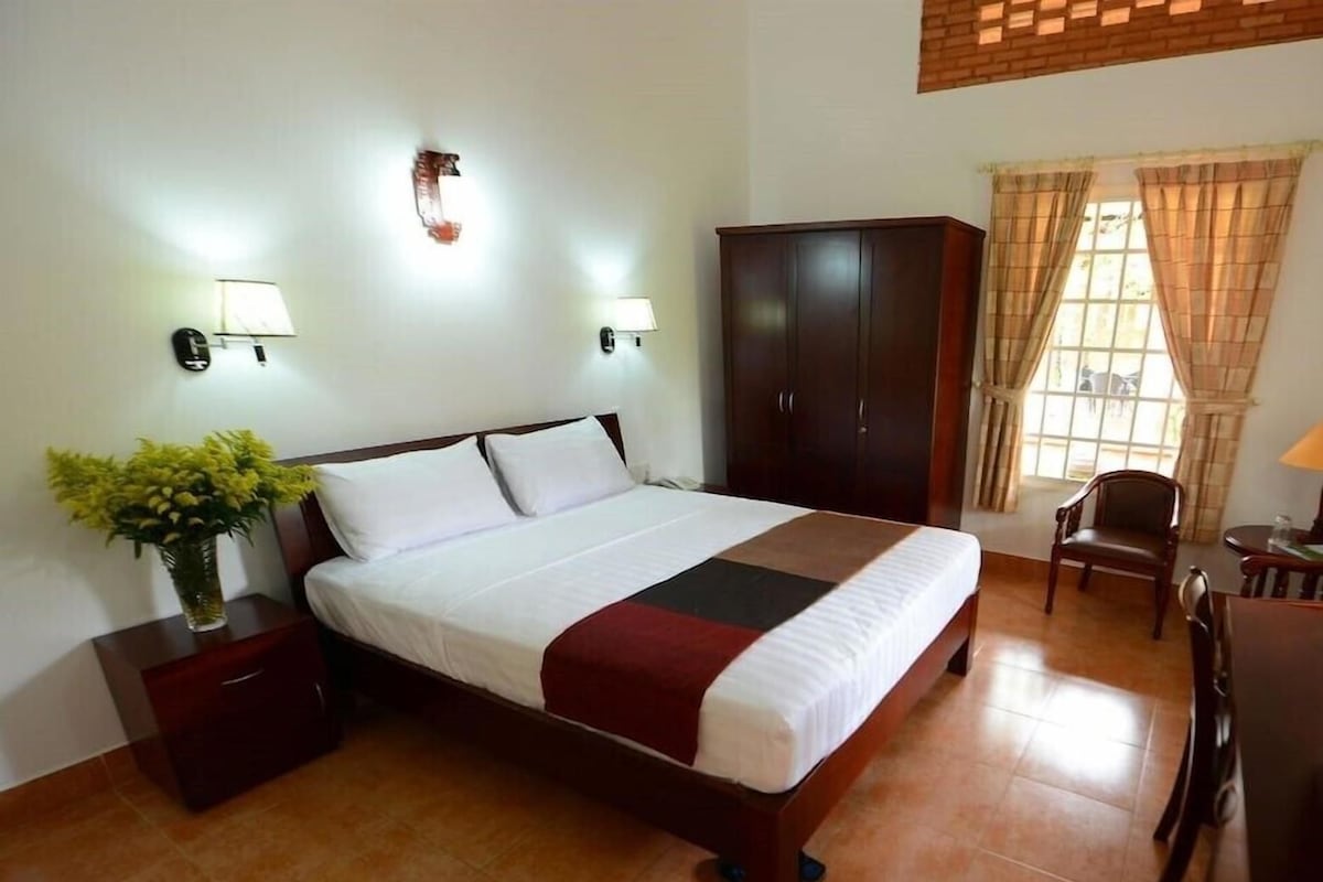 Une chambre d’hôtel comprenant un lit, des tables de chevet, une armoire, un bureau et une chaise.
