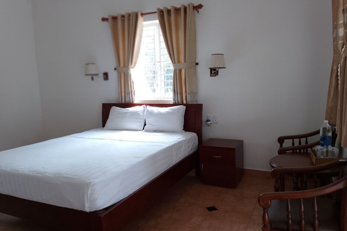 Un lit simple avec un cadre en bois, une table de chevet, une chaise et une lampe.